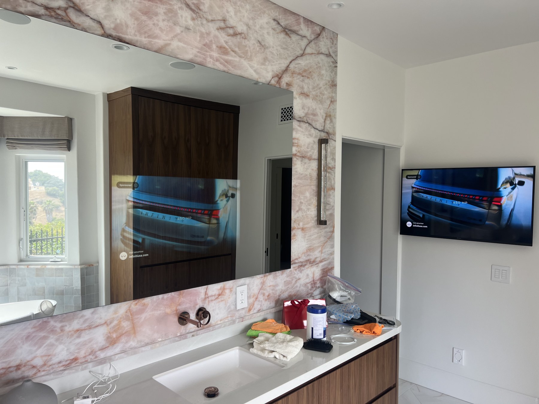 Séura mirror television and coordinated wall television in a marble bathroom